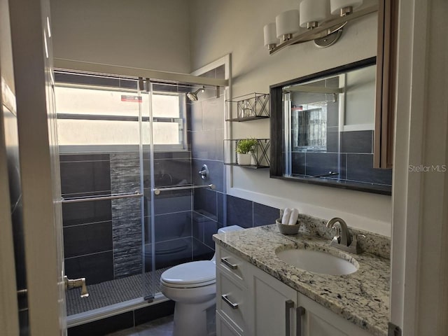 bathroom featuring toilet, vanity, a shower with door, and tile walls