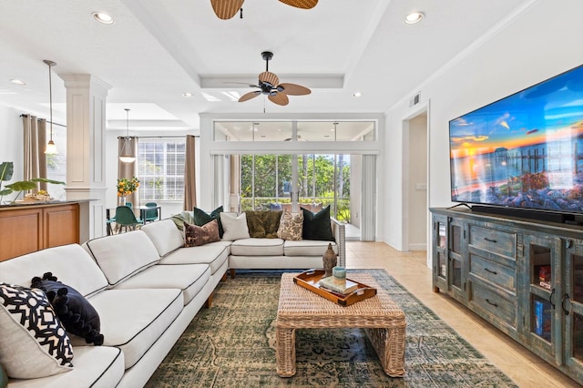 tiled living room with a tray ceiling, a wealth of natural light, ornamental molding, and ornate columns