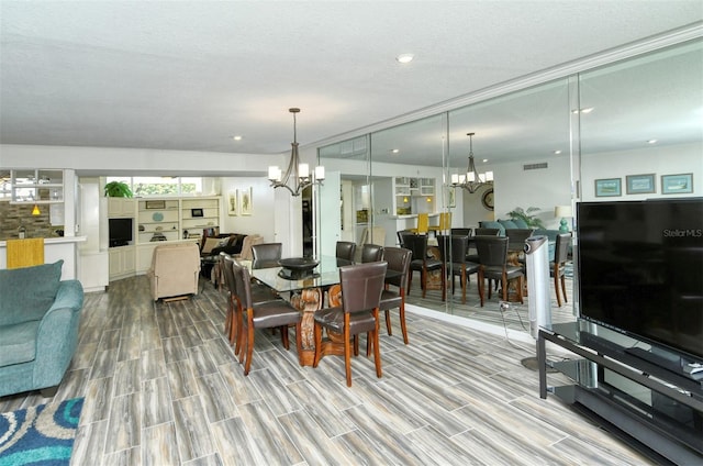 dining area featuring an inviting chandelier, a textured ceiling, and light wood-type flooring