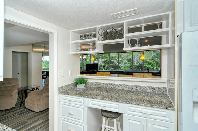 bar with a healthy amount of sunlight, white cabinets, a textured ceiling, and white refrigerator