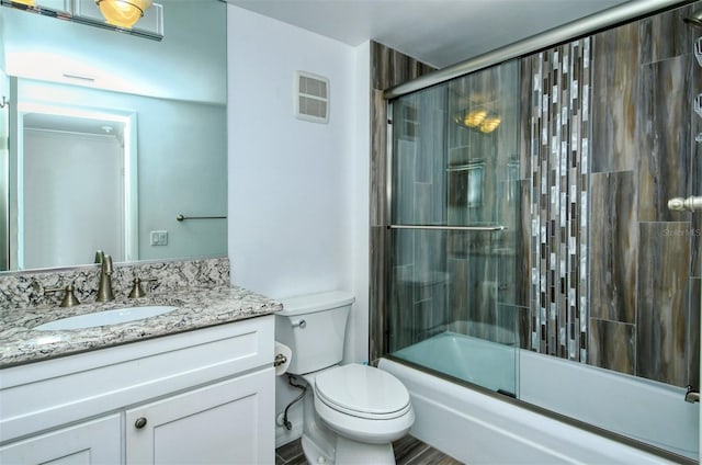 full bathroom with bath / shower combo with glass door, toilet, and vanity