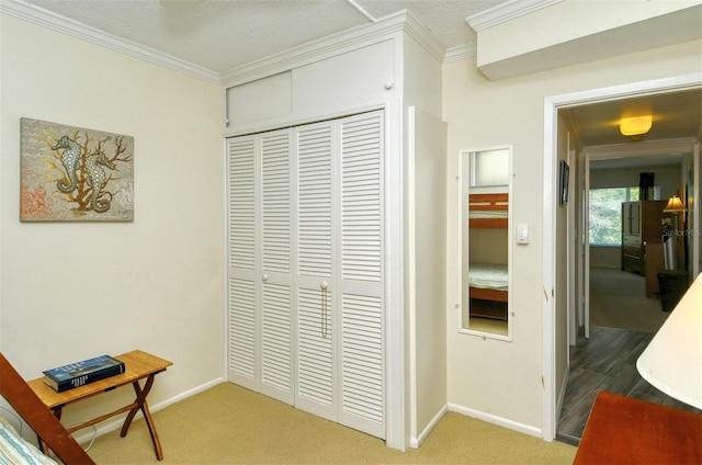 hall with carpet flooring, ornamental molding, and a textured ceiling