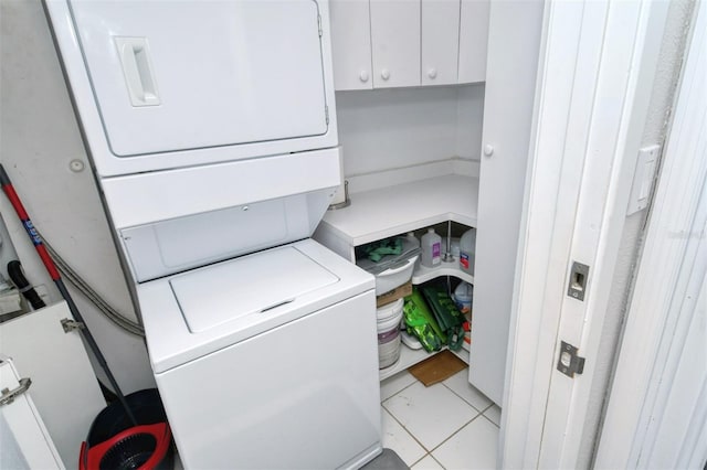 clothes washing area with stacked washer / drying machine and light tile flooring