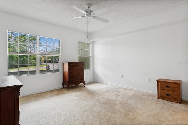 interior space with light colored carpet, ceiling fan, and a textured ceiling