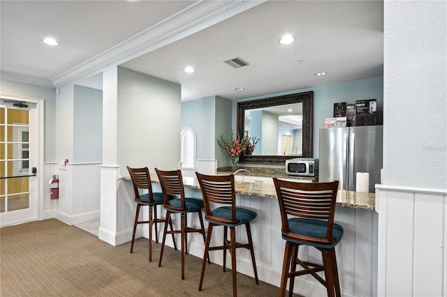 bar with stainless steel refrigerator, light carpet, and stone counters