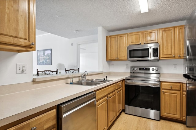 kitchen with sink, light hardwood / wood-style flooring, a textured ceiling, and appliances with stainless steel finishes