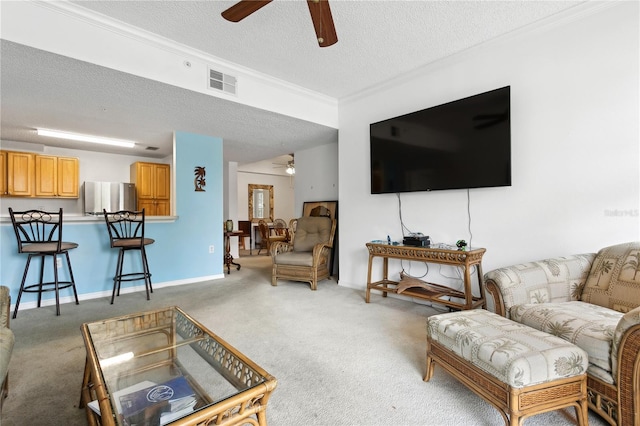 carpeted living room with ceiling fan, a textured ceiling, and ornamental molding