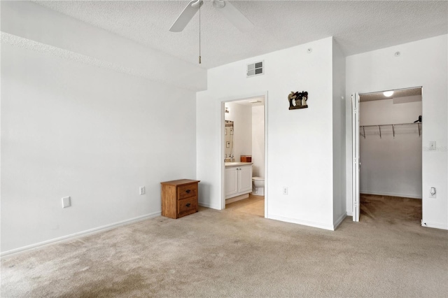 unfurnished bedroom featuring a walk in closet, a closet, connected bathroom, and light colored carpet