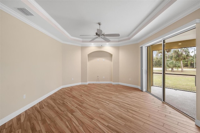 spare room with light hardwood / wood-style floors, a tray ceiling, ornamental molding, and ceiling fan