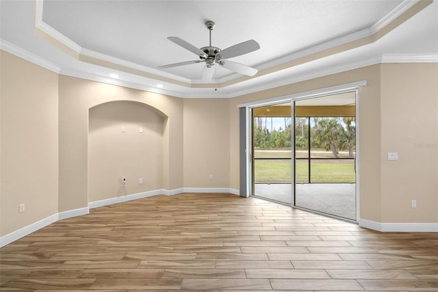 unfurnished room featuring crown molding, light hardwood / wood-style flooring, a tray ceiling, and ceiling fan