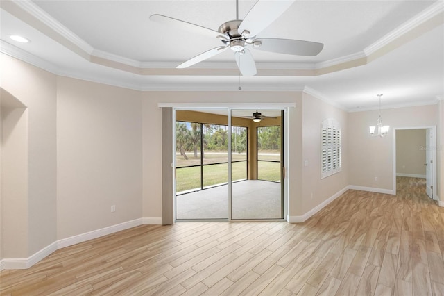 unfurnished room featuring crown molding, an inviting chandelier, light hardwood / wood-style flooring, and a tray ceiling