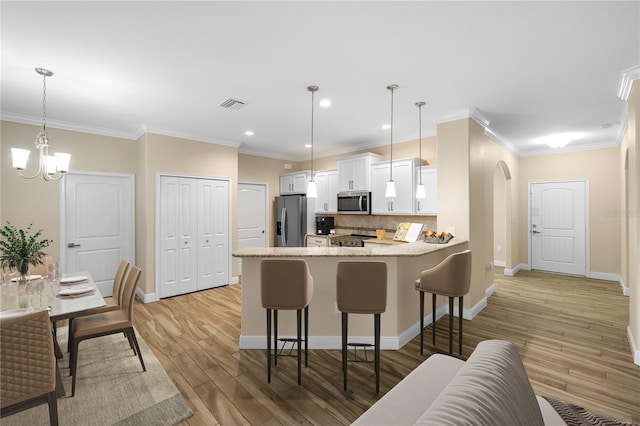 kitchen featuring kitchen peninsula, white cabinets, pendant lighting, and appliances with stainless steel finishes