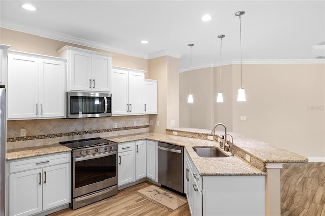 kitchen with kitchen peninsula, appliances with stainless steel finishes, sink, decorative light fixtures, and white cabinets