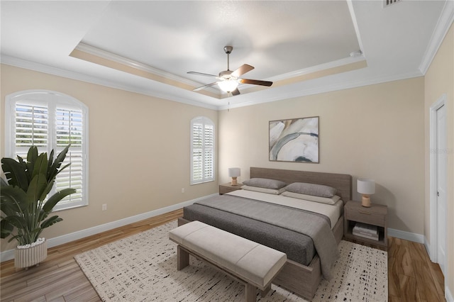 bedroom featuring ornamental molding, ceiling fan, a raised ceiling, and light hardwood / wood-style flooring