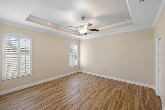 empty room featuring ceiling fan, light hardwood / wood-style flooring, crown molding, and a tray ceiling