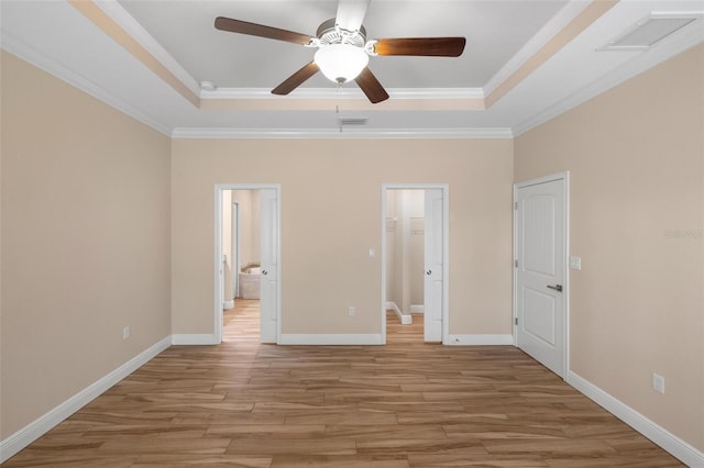 unfurnished bedroom with ensuite bathroom, a raised ceiling, light hardwood / wood-style flooring, ornamental molding, and ceiling fan