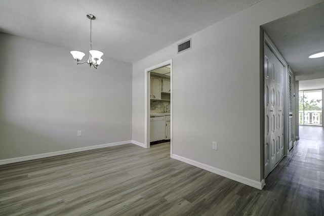 unfurnished room featuring visible vents, dark wood-style floors, baseboards, and a chandelier