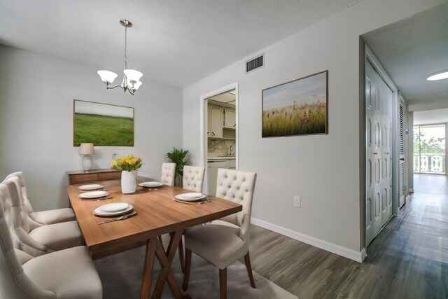 dining room featuring dark wood finished floors, a notable chandelier, baseboards, and visible vents