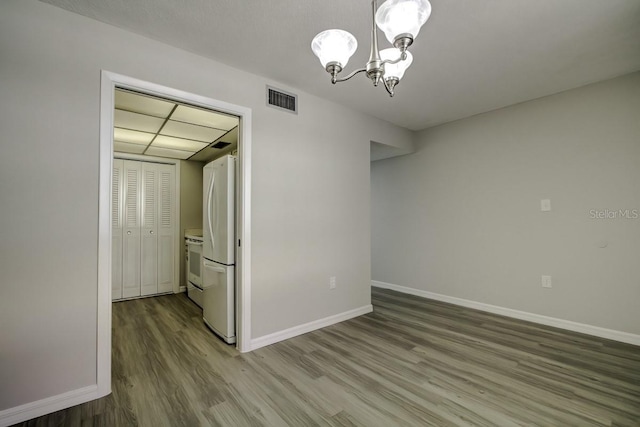 interior space featuring baseboards, wood finished floors, visible vents, and a chandelier