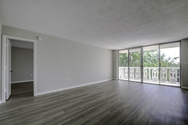 spare room with a wall of windows, dark wood-style floors, baseboards, and a textured ceiling