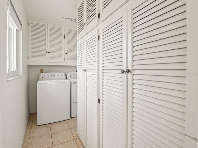 laundry area featuring washer and dryer, light tile patterned floors, and cabinets