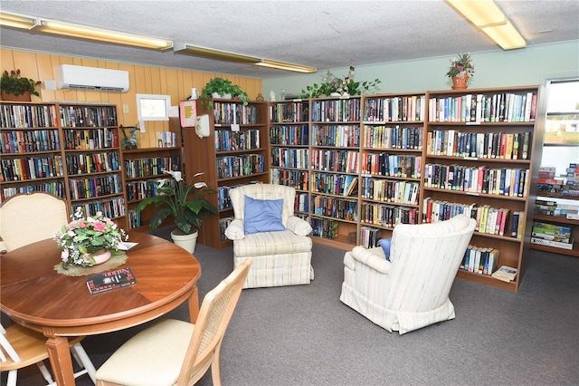 living area featuring an AC wall unit, a textured ceiling, and carpet flooring