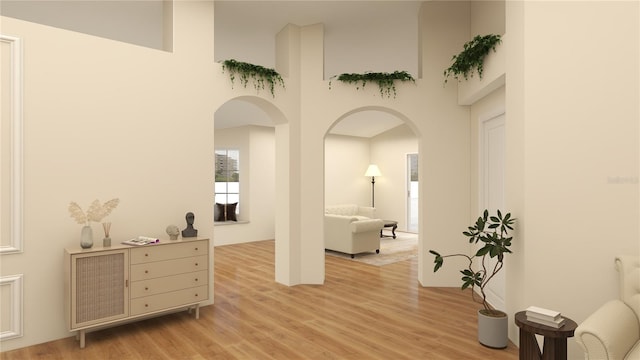 corridor featuring a towering ceiling and light hardwood / wood-style floors