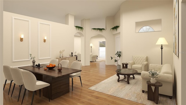 living room featuring a towering ceiling, plenty of natural light, and light hardwood / wood-style flooring