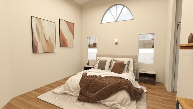 bedroom featuring a towering ceiling and hardwood / wood-style floors