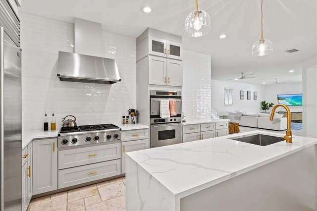 kitchen with ceiling fan, sink, hanging light fixtures, wall chimney range hood, and appliances with stainless steel finishes