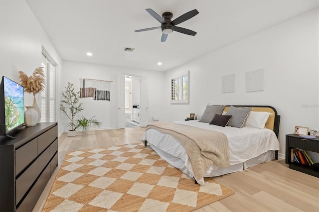 bedroom featuring light hardwood / wood-style floors, ceiling fan, and ensuite bathroom