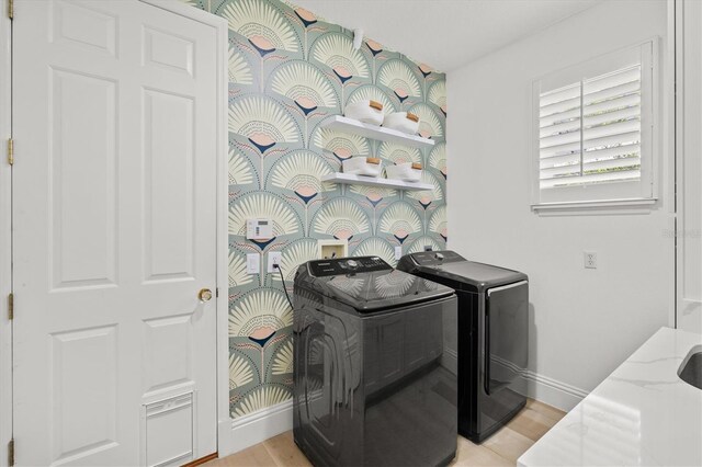 laundry area with washing machine and clothes dryer and light hardwood / wood-style floors