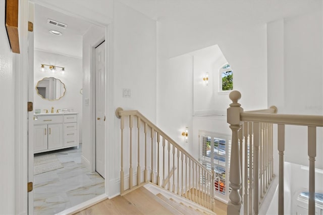 stairway with hardwood / wood-style floors, a healthy amount of sunlight, and sink