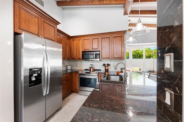 kitchen with decorative light fixtures, stainless steel appliances, dark stone counters, sink, and beam ceiling