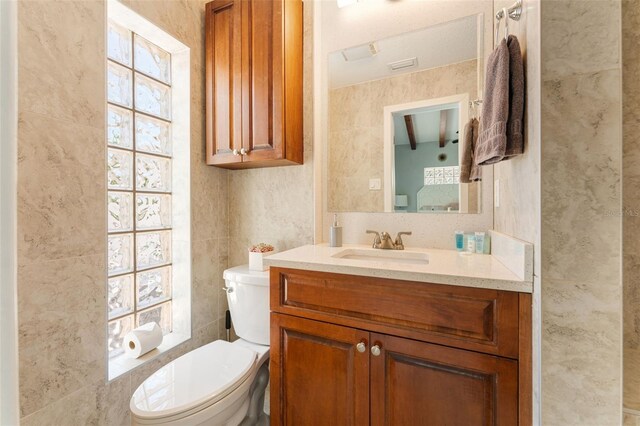 bathroom with toilet, vanity, and plenty of natural light