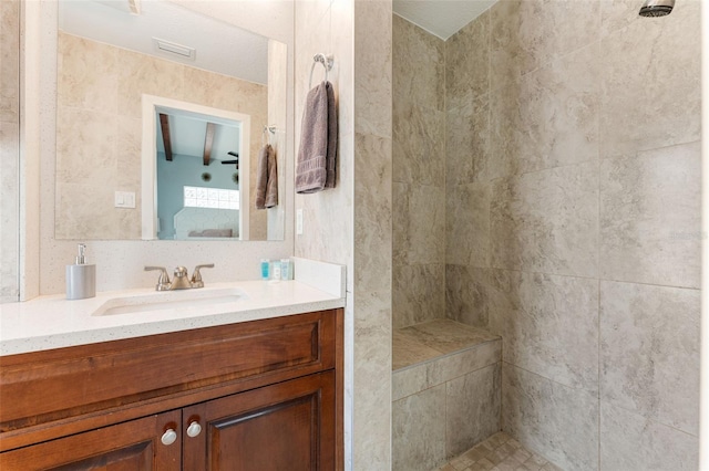 bathroom featuring a tile shower and vanity