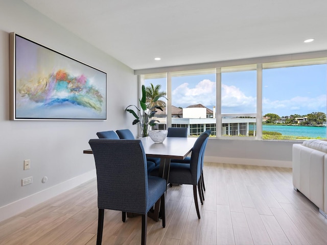 dining space with a water view and light hardwood / wood-style flooring