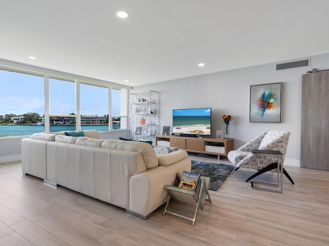 living room featuring a water view and light hardwood / wood-style flooring