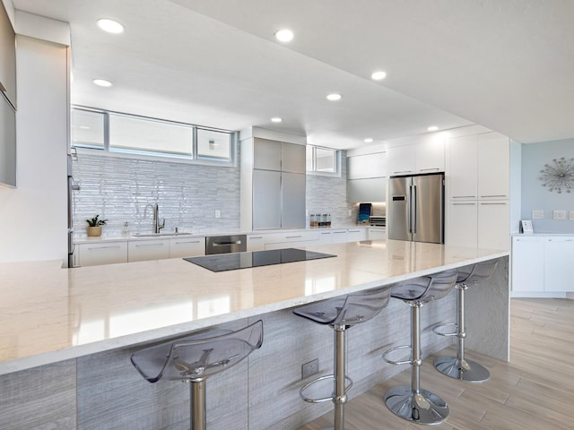 kitchen with kitchen peninsula, light stone counters, a breakfast bar, and stainless steel appliances