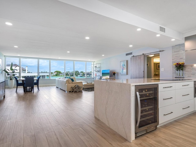 kitchen with a barn door, light hardwood / wood-style floors, white cabinetry, and beverage cooler