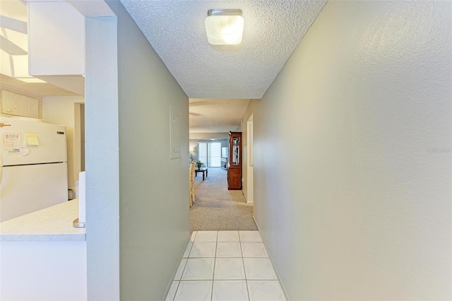 hall with a textured ceiling and light tile flooring