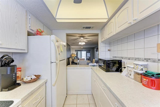 kitchen with light tile flooring, backsplash, white fridge, ceiling fan, and a textured ceiling