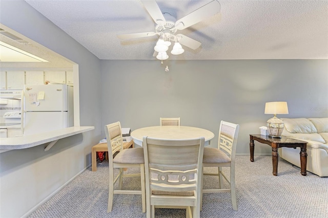 dining room featuring light carpet, ceiling fan, and a textured ceiling