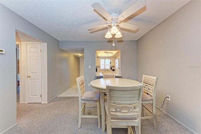 carpeted dining space with ceiling fan and a textured ceiling