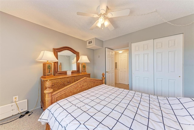 bedroom with a closet, ceiling fan, carpet flooring, and a textured ceiling