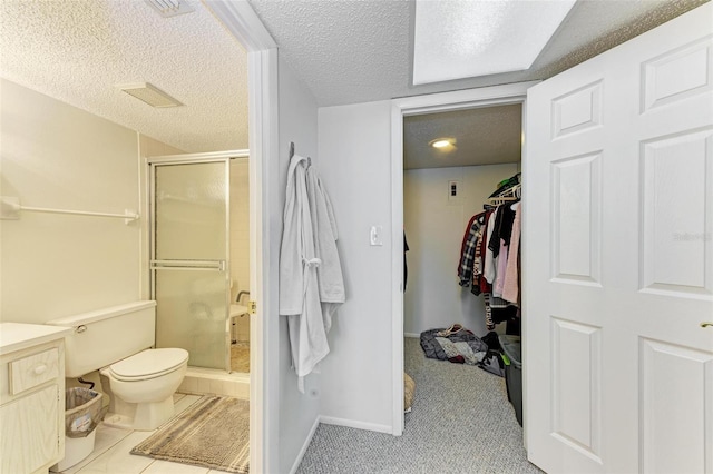 bathroom featuring tile flooring, a textured ceiling, toilet, a shower with shower door, and vanity