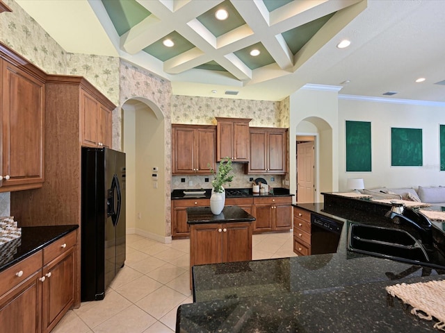 kitchen featuring dark stone counters, a center island, black appliances, sink, and ornamental molding