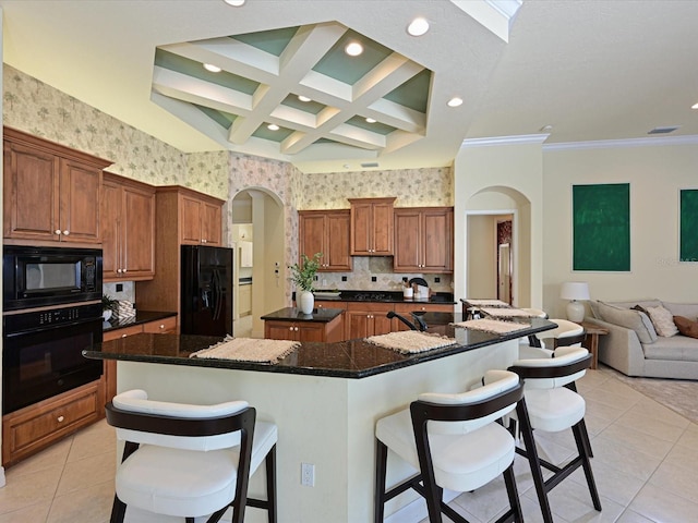 kitchen with black appliances, a kitchen bar, dark stone countertops, a spacious island, and coffered ceiling