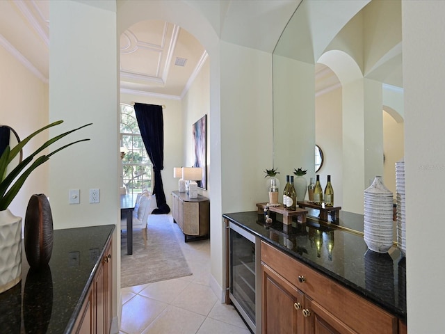 bar with wine cooler, dark stone countertops, light tile patterned floors, and ornamental molding