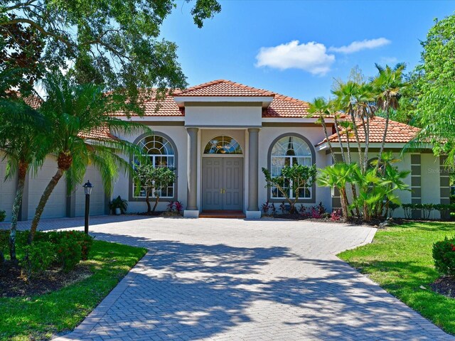 mediterranean / spanish home featuring a garage and a front lawn